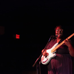 artist playing bass and singing on stage