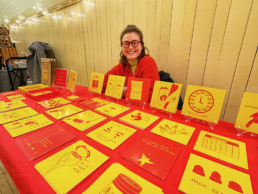 Artist with red and yellow prints on a table.