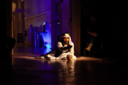 performer on floor with outstretched hand and dramatic lighting