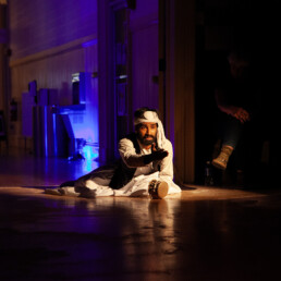 performer on floor with outstretched hand and dramatic lighting