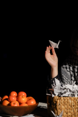 hand, oranges and folder origami crane